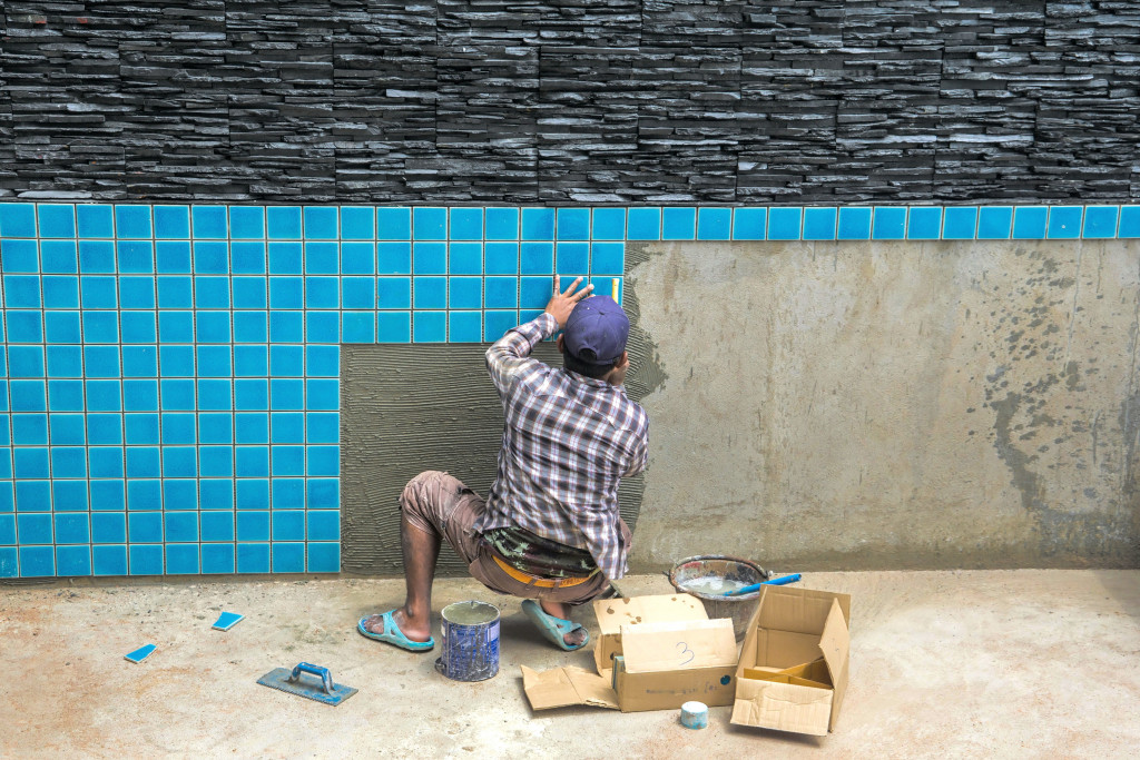Photo of a man installing tiles for a swimming project