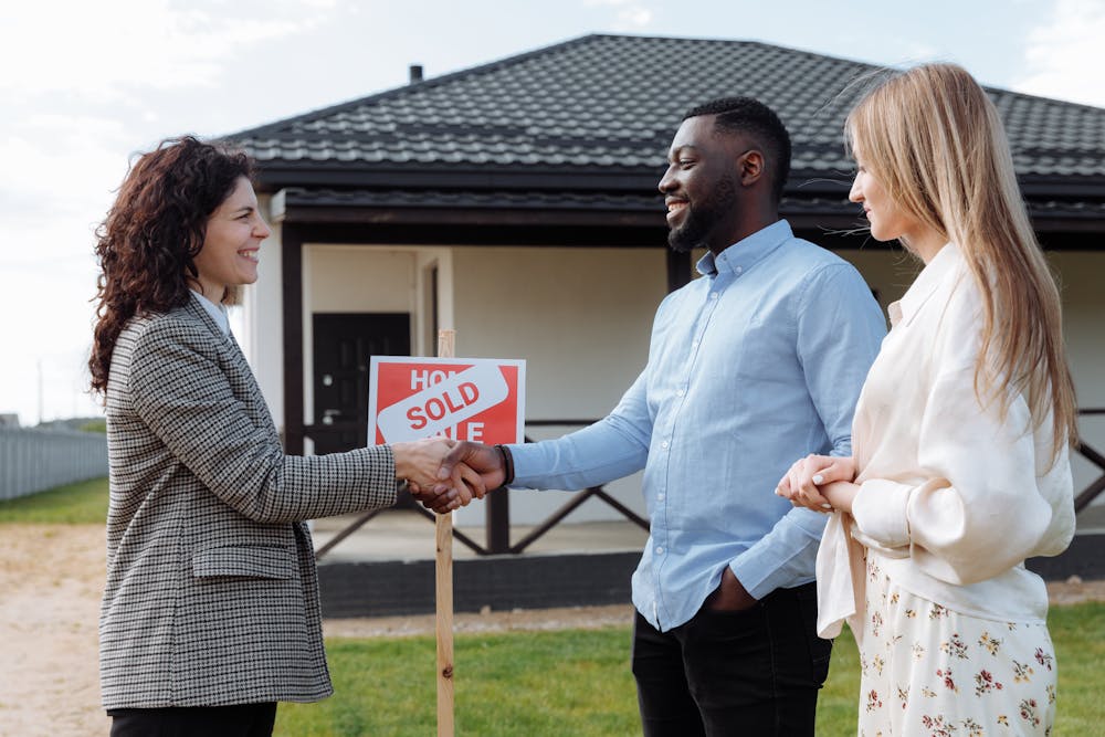 a couple and a real estate agent doing a handshake